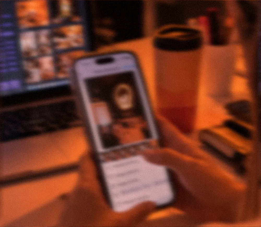 Miembro del equipo de Frato revisando publicaciones en el celular frente al computador